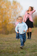 © Anna - boy runs against the background of his mother and brother, in the autumn park for a walk