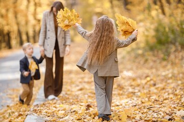 Wall Mural - Mother and her children playing and having fun in autumn forest