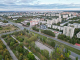 Fototapeta Do pokoju - Panoramic view from the drone of a walking park near residential buildings. Urban landscape, bird's-eye view from the park. Cloudy weather over the city.