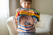 © urika - boy holding a stack of clothes. Kids clothing fashion.