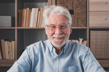 Portrait of one old cheerful male senior smiling having fun at home. Mature caucasian man studying independent looking at the camera and posing to picture..