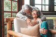 © Daniel - Portrait of couple of happy mature people in love hugging and looking at the camera smiling and having fun at home. Two cute seniors enjoying indoors together.