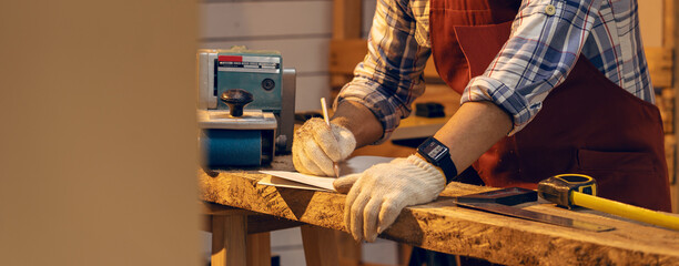 Carpenter man working use pencil sketching design woodwork furniture in carpentry workshop. Craftsman and DIY handmade.