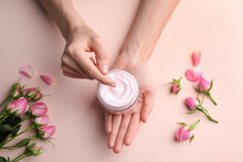 Woman Holding Jar Of Hand Cream On Pink Background, Top View