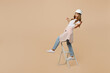 Full body young employee laborer handyman woman in white t-shirt helmet stand on stepladder lean back isolated on plain beige background Instrument accessories for renovation room Repair home concept