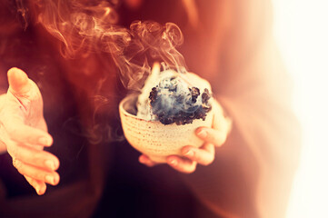 Shaman Hands. A spiritual woman holding burning sage smudge. 