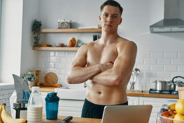 Sticker - Confident young man looking at camera while preparing healthy food at the kitchen