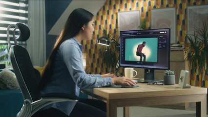 Poster - Asian woman editing photo in photoshop for customer on personal computer while sitting at the table at home office and working remotely