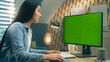 © Framestock - Asian woman sitting at the table and looking at screen of personal computer while working remotely from home or surfing the internet. Freelance. Green screen and chromakey