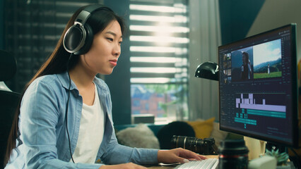 Poster - Female asian freelancer editing video for customer or travel blogger in program on computer while sitting at the table and working at home