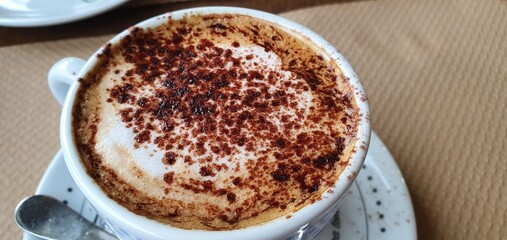 Aromatic coffee with foam and chocolate. Delicious cappuccino in a cup. Nice foamy coffee. Coffee foam on a spoon.