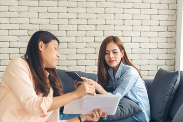 Wall Mural - Two businesswomen team meeting using laptop at company office desk. Two young Female freelance reading financial graph charts Planning analyzing marketing data. Asian people team working office firm.