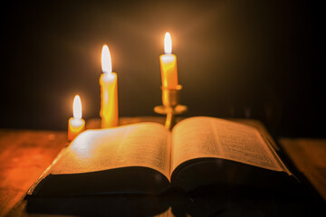 Canvas Print - Light candle with holy bible and cross or crucifix on old wooden background in church.Candlelight and open book on vintage wood table christianity study and reading in home.Concept of christ religion