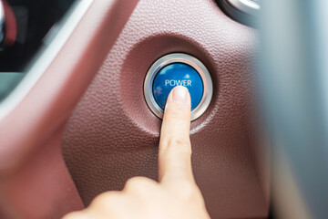 Finger press a car ignition button or START engine inside modern electric automobile. Keyless, change, strategy, vision, innovation and future concept