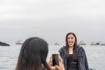 woman grimacing while her friend takes a photo with the mobile on a boat