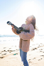 Cheerful Girl Playing Guitar Standing At Beach