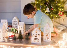 Boy Playing With Toy Train Near Christmas Tree At Home