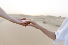 Couple Holding Hands In Desert At Sunset