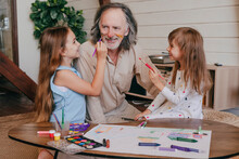 Granddaughters Having Fun Painting Grandfather's Face At Home