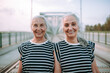 © Halfpoint - Portrait of happy seniors women, twins in same clothes, walking on city bridge.