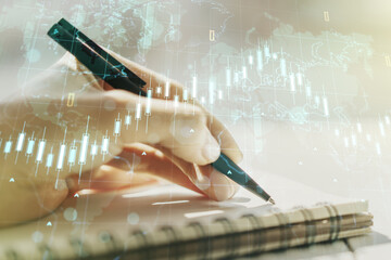 Poster - Abstract creative financial graph with world map and with woman hand writing in diary on background, financial and trading concept. Multiexposure