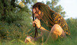 Young man with long dreadlock hitting stone on stone to make a primal fire. Survival in nature concept.