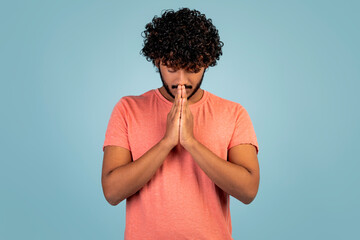 Wall Mural - Eastern young man holding hands by his mouth, praying