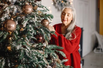 Senior woman standing and decorating christmas tree