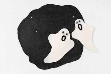 Funny ghost made from plasticine for the holiday of Halloween on white background. Sensory play for toddlers. Holiday Art Activity for Kids.