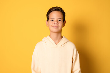 Wall Mural - Happy young caucasian boy in casual outfit isolated over yellow background