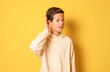 © Danko - Little caucasian boy isolated on yellow background listening to something by putting hand on the ear