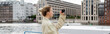 © LIGHTFIELD STUDIOS - Side view of woman in trench coat taking photo on mobile phone in Berlin, banner.