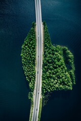 Wall Mural - Aerial view of road through blue lakes or sea with green woods in Finland.