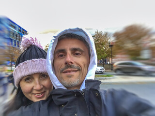 Wall Mural - Happy couple taking selfies in a city street, autumn season