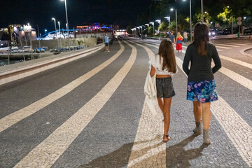 Sticker - Woman walking along the city promenade at night with her daughter