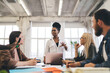 © BullRun - Cheerful black woman talking with diverse colleagues