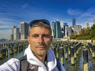 Poster - Happy male tourist visiting New York City, Lower Manhattan in the background