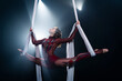 A young girl performs the acrobatic elements in the aerial silk. Studio shooting performances on a black background