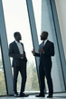 © pressmaster - Young confident African American male employee in elegant suit explaining something to colleague at meeting in office center