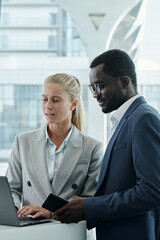 Aufkleber - Young confident female broker in elegant grey suit discussing online data with colleague while both looking at laptop screen at meeting