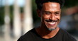 © Marco - Black man laughing out loud reacting to joke. African person standing outside in the sunlight
