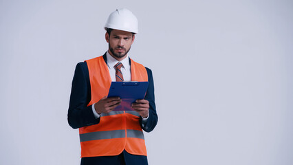 Sticker - serious contractor in hardhat holding clipboard and looking away isolated on grey.