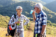 Two senior adult have pause on hiking and drink water and smile in natural environment