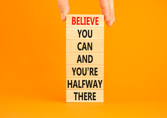 Wall Mural - You can symbol. Concept words Believe you can and you are halfway there on wooden blocks on a beautiful orange table orange background. Businessman hand. Business motivational and you can concept.