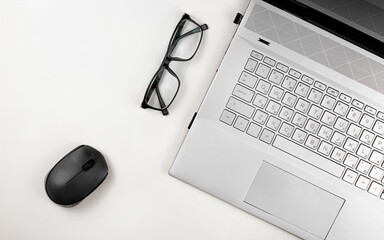 Poster - A laptop with glasses and computer mouse are on a white table. Top view with copy space