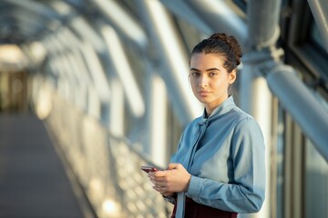 Wall Mural - Ai generated face of young brunette female delegate looking at you while scrolling in mobile phone in front of camera