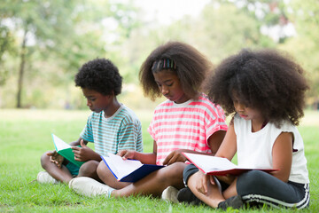 Wall Mural - Group of happy African American children reading a book outdoors in the park. Kids girl learning outside at the school