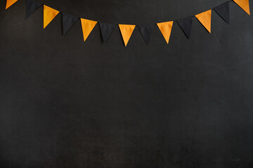 Halloween garland of black and orange flags on a dark background with space for text