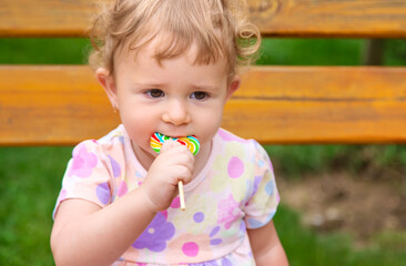 Poster - Baby eats a lollipop in the park. Selective focus.