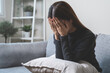 © Pormezz - Unhappy anxiety young Asian woman covering her face with pillow on the cough in the living room at home.